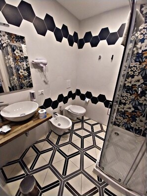 Un baño con suelo de baldosas hexagonales, lavabo, bidé, inodoro y ducha.
