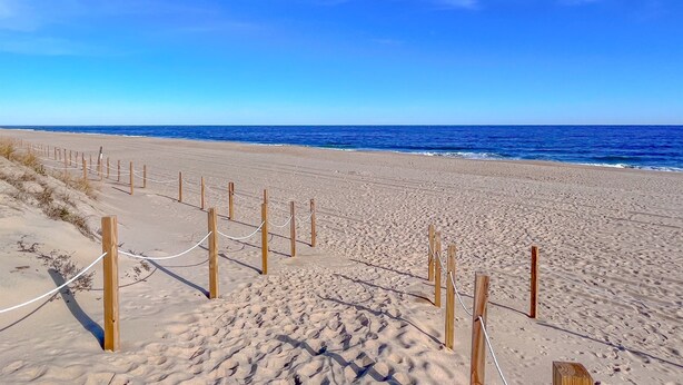 A sandy beach with wooden posts and ropes forming a barrier.