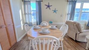A dining area with a wooden table, white chairs, and a beige sofa.