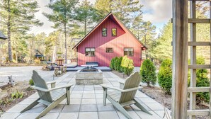 A red cabin with a stone fireplace, two Adirondack chairs, and a stone bench in front. - Charming Tamworth Cabin w/ Grill & Fireplace (Tamworth)