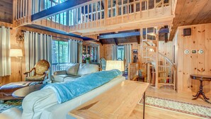 A spacious cabin with a loft bedroom, a cozy living area with a sofa and armchairs, and a dining table. - Charming Tamworth Cabin w/ Grill & Fireplace (Tamworth)