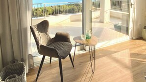 Ein modernes Wohnzimmer mit einem großen Schiebeglasfenster, das auf einen Balkon mit herrlichem Meerblick führt.