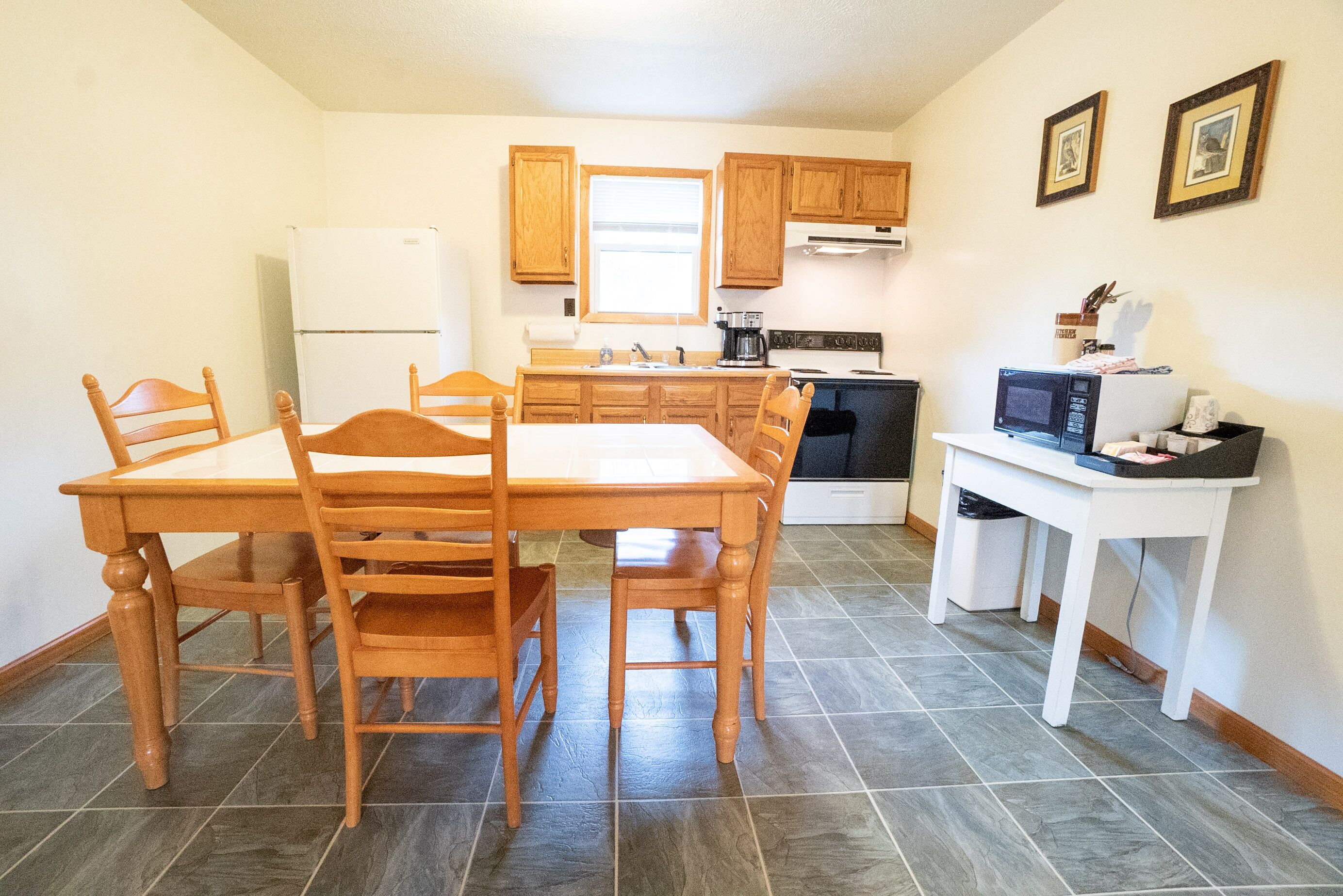 A compact kitchen with wooden cabinets, a white refrigerator, a stove, and a microwave.