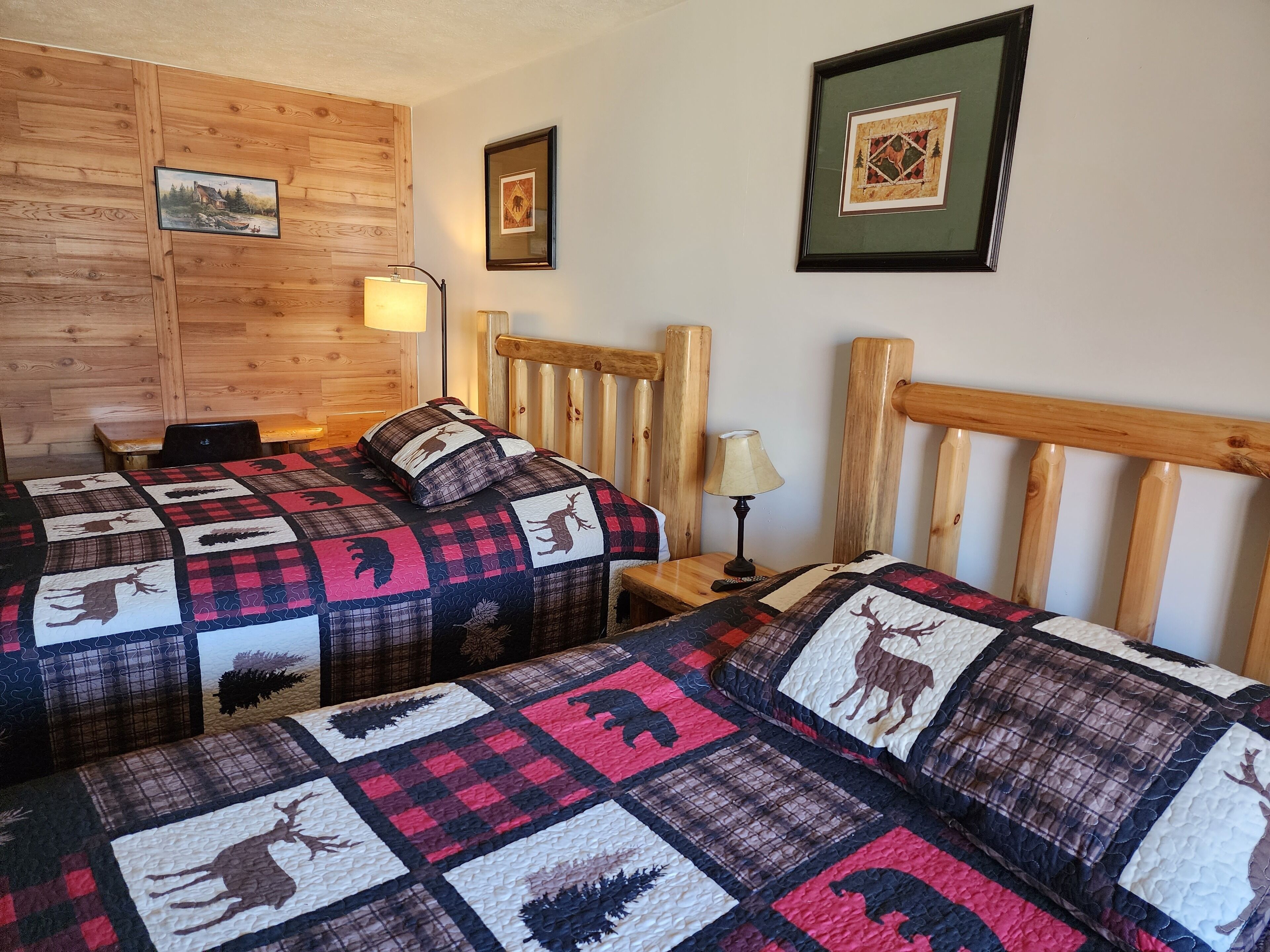 Ein gemütliches Zimmer mit zwei Betten, Holz-Kopfteilen und einer gesteppten Bettdecke mit Tiermotiven.