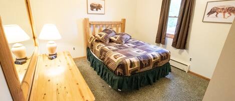 A bedroom with a wooden bed, a dresser, a mirror, and two wall-mounted lamps.