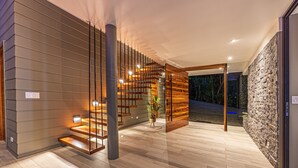 Un interior modern amb una escala de fusta, una paret de pedra i un paviment de fusta.