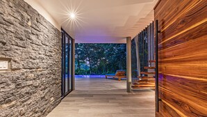 Un passadís modern amb paret de pedra, revestiment de fusta i vista a arbres.