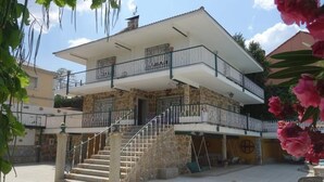 A two-story building with a stone facade, a balcony on the upper floor, and a staircase leading to the entrance. - Suyoluce, Chalet con Piscina Privada El Escorial (El Escorial)