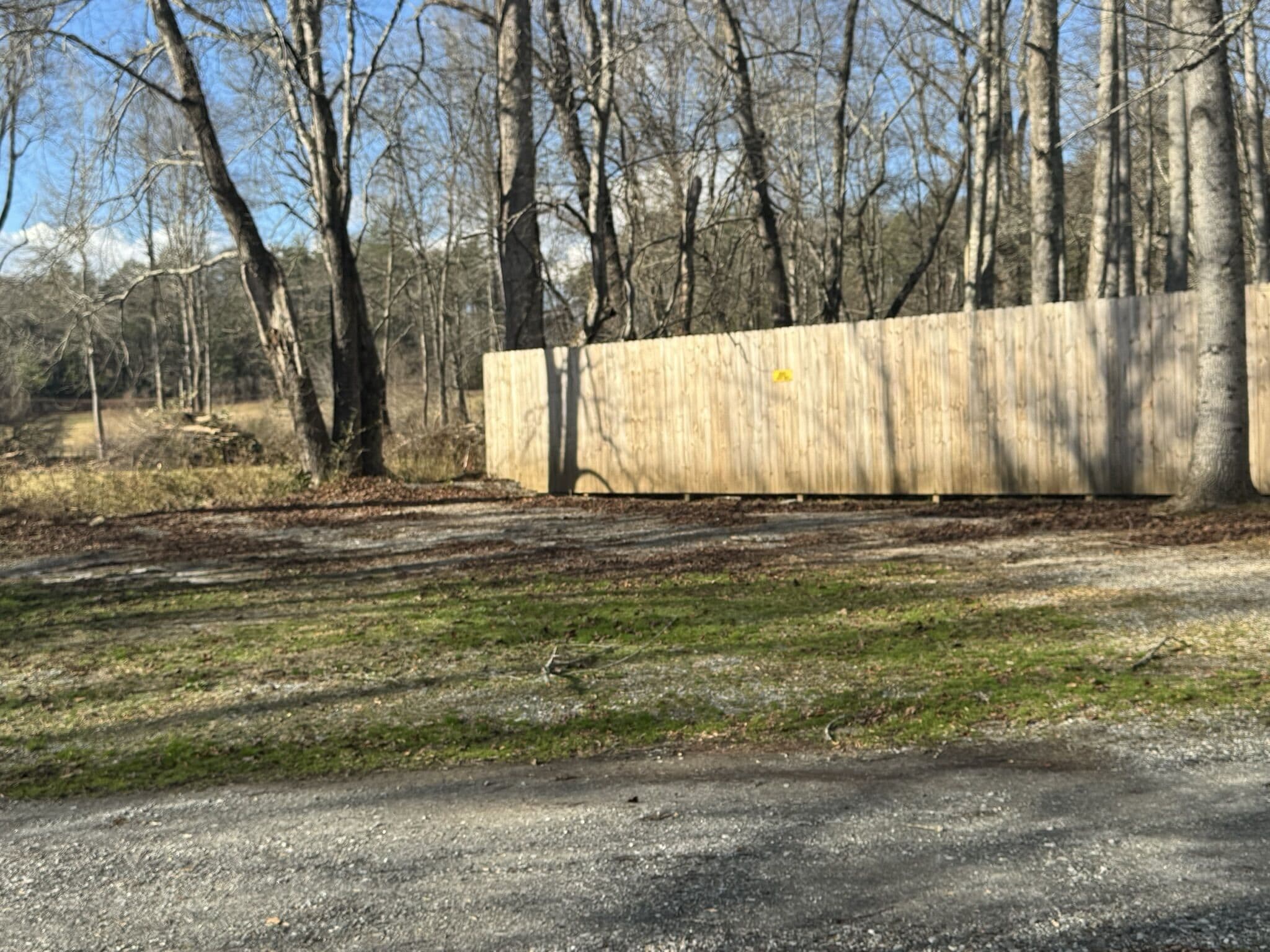 A paved path leading to a wooden fence in a wooded area.