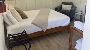 Un dormitorio con una cama, una silla, un televisor y un extintor.