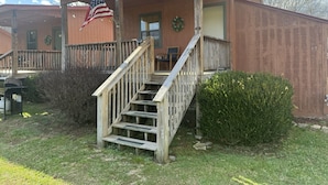 Un edificio de madera con un porche, una bandera y una escalera.