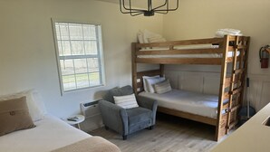 Une pièce comprenant un lit superposé, un canapé, une chaise et une petite table.