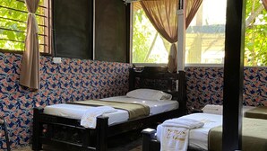 Een kamer met twee bedden, een bankje en een tafel.