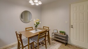 Ein Essbereich mit Holztisch, Stühlen, einer Blumenvase, einem Spiegel und einer Pendelleuchte.