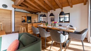 Una cocina moderna con armarios de madera y un comedor con una mesa de madera y sillas grises.
