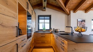 Una cocina moderna con armarios de madera, encimera negra y ventana con persianas.
