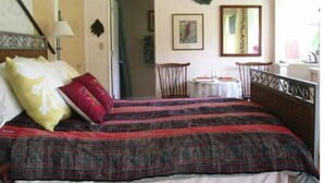A bedroom with a bed, a chair, a table, and a mirror.