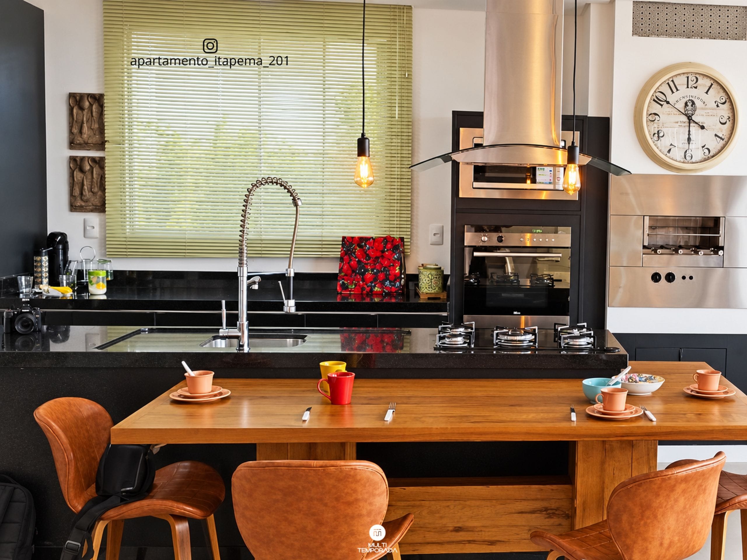 Una cocina moderna con una isla central, electrodomésticos de acero inoxidable y un reloj de pared grande.