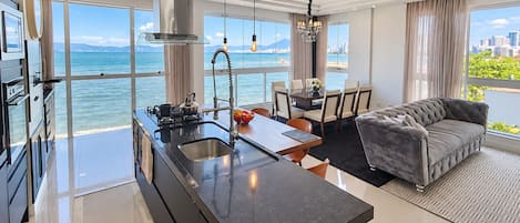 A modern kitchen with a large island, a dining area with a view, and a living room with a sofa.