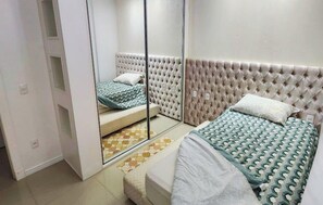 Een slaapkamer met twee bedden, een spiegel en een kamerkleed met dessin.
