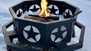 A hexagonal outdoor fire pit with a burning fire in a snowy landscape.