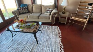 A living room with a sofa, a coffee table with flowers, a lamp, and a chair.