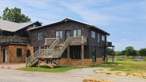 A two-story log cabin with a balcony and a stone foundation.