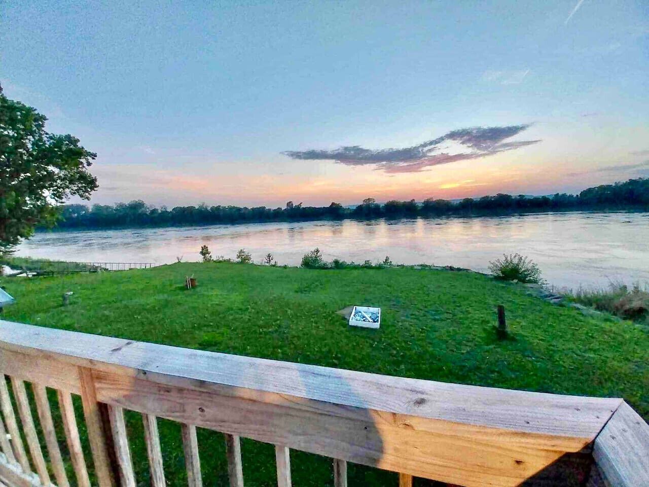 Une zone herbeuse avec une terrasse en bois donnant sur une rivière.