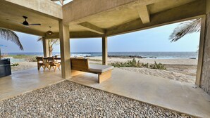 A beachside lounge with a concrete ceiling, a ceiling fan, and a view of the ocean.