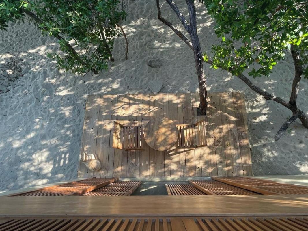 Une terrasse en bois avec des bancs, un mur en pierre et un arbre.