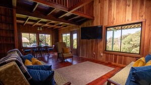 A wooden interior with a TV, seating area, and large windows. - Mountain Wonders Chalet: Perfect to enjoy nature (Provincia de Puntarenas)