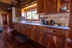 Una cocina con armarios de madera, una encimera, un fregadero, una cafetera y una ventana.