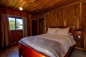 Habitación con paneles de madera, una cama, una ventana y una puerta.