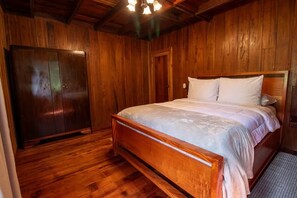 Une piÚce aux murs lambrissés, comprenant un lit, une armoire et une porte.