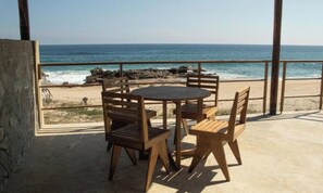 A wooden table and chairs on a balcony with a view of the ocean. - Utopía Beach Suite Sunset (Agua Blanca)
