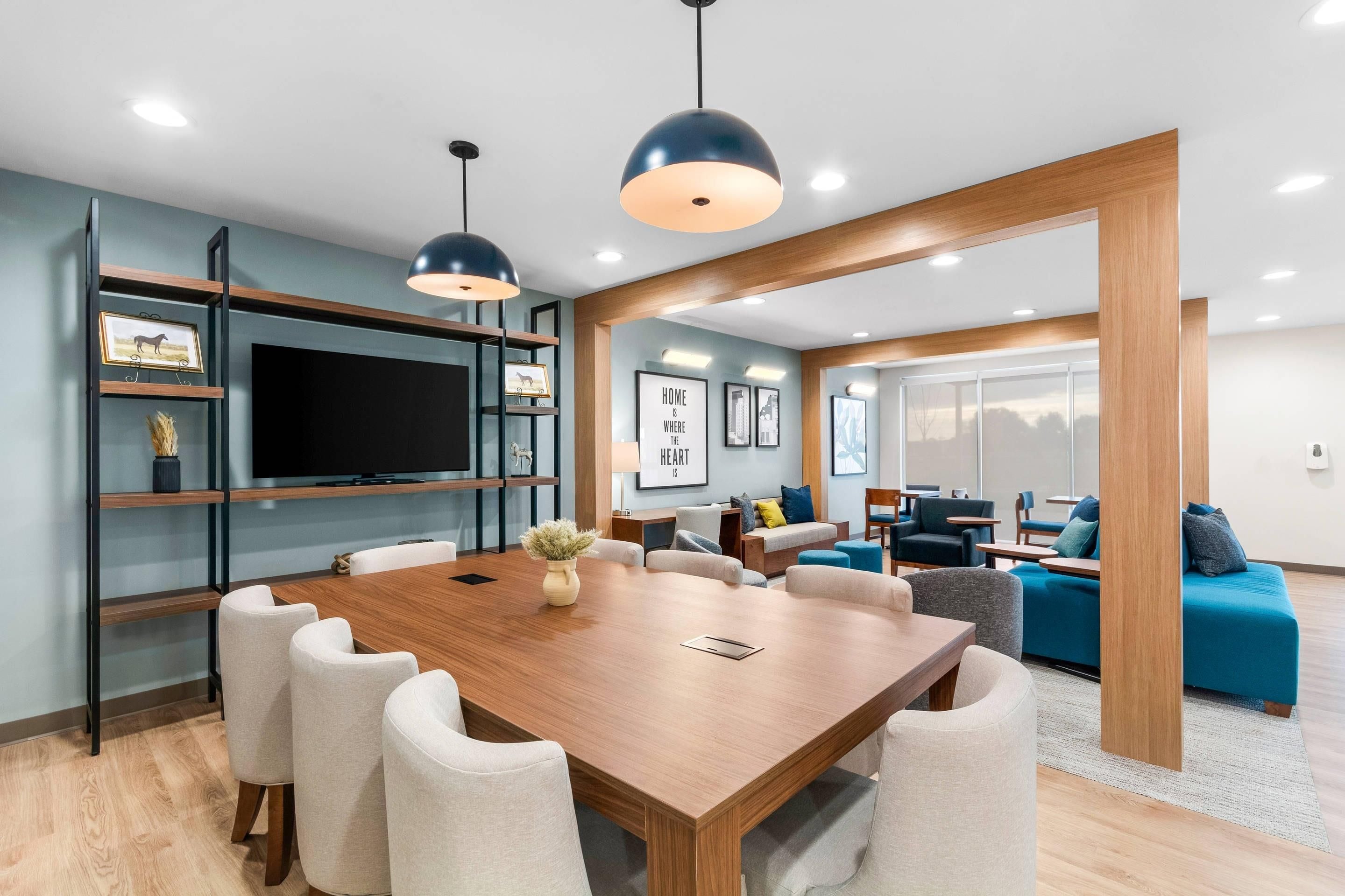 A modern living room with a wooden dining table, comfortable seating, and a television.