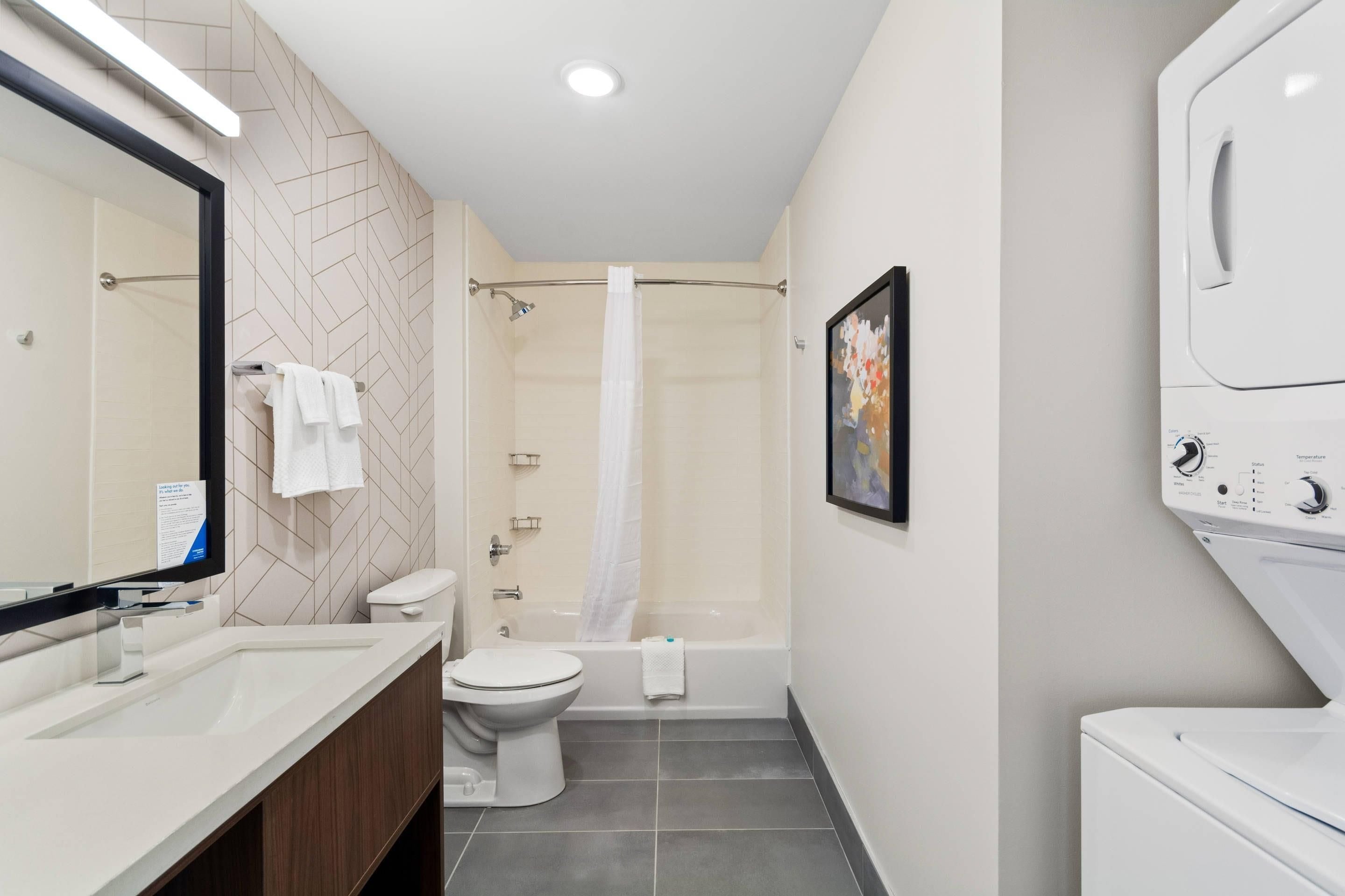 Ein modernes Badezimmer mit Dusche, Toilette und einer integrierten Waschmaschine.
