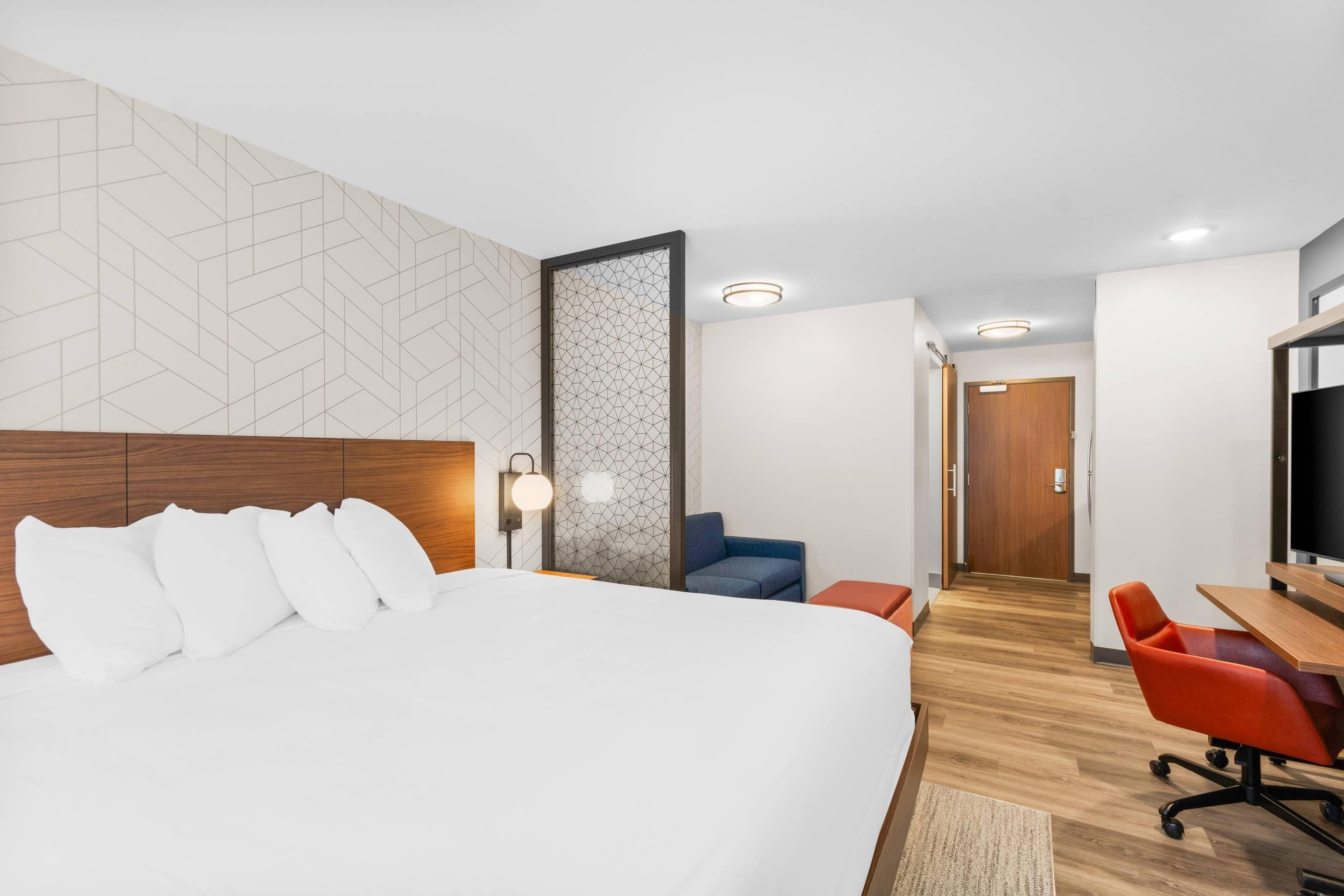 Una habitación de hotel con una cama grande, un escritorio, una silla y un televisor.