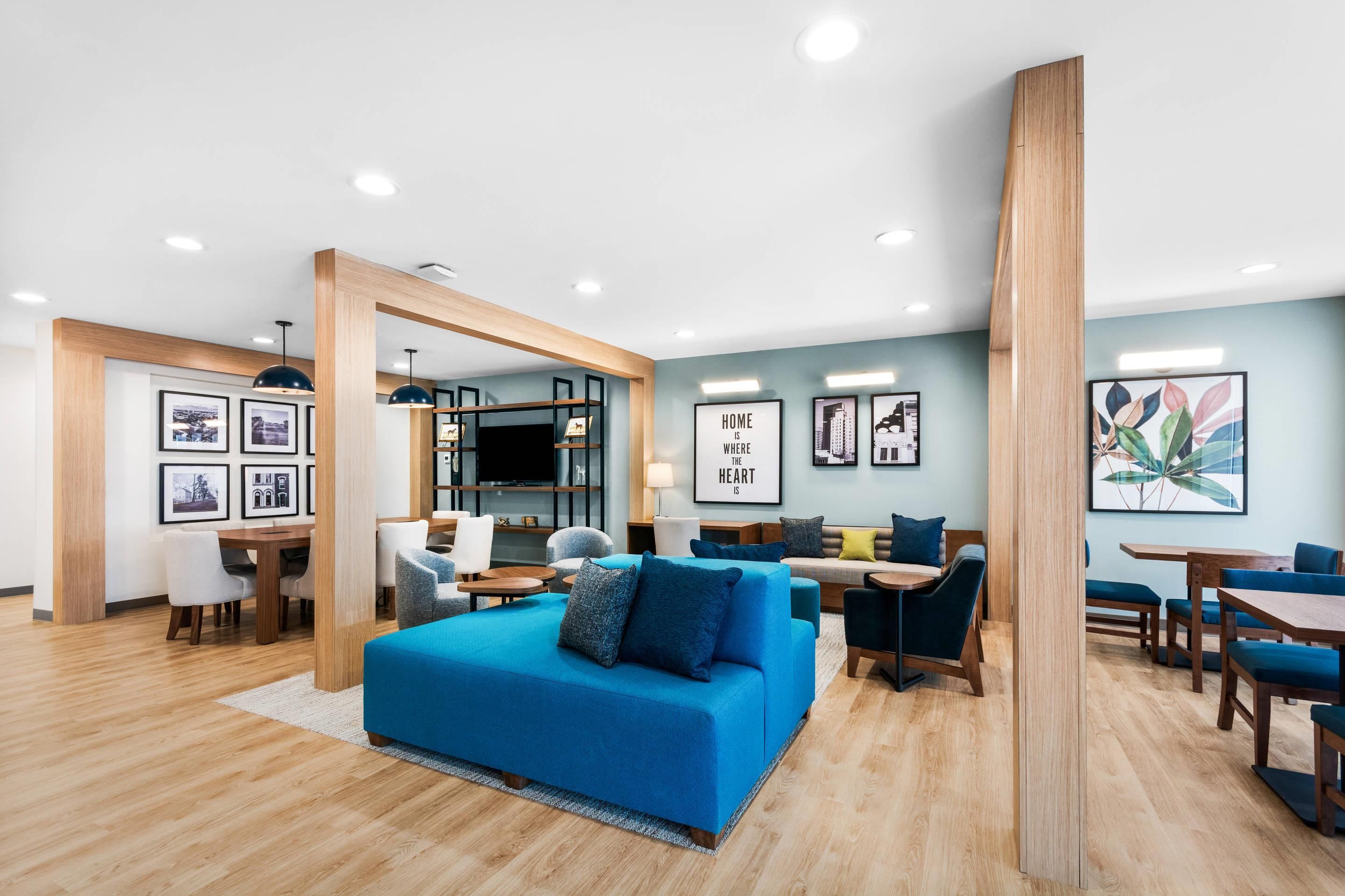 A modern living room with a blue sofa, wooden accents, and framed pictures on the walls.