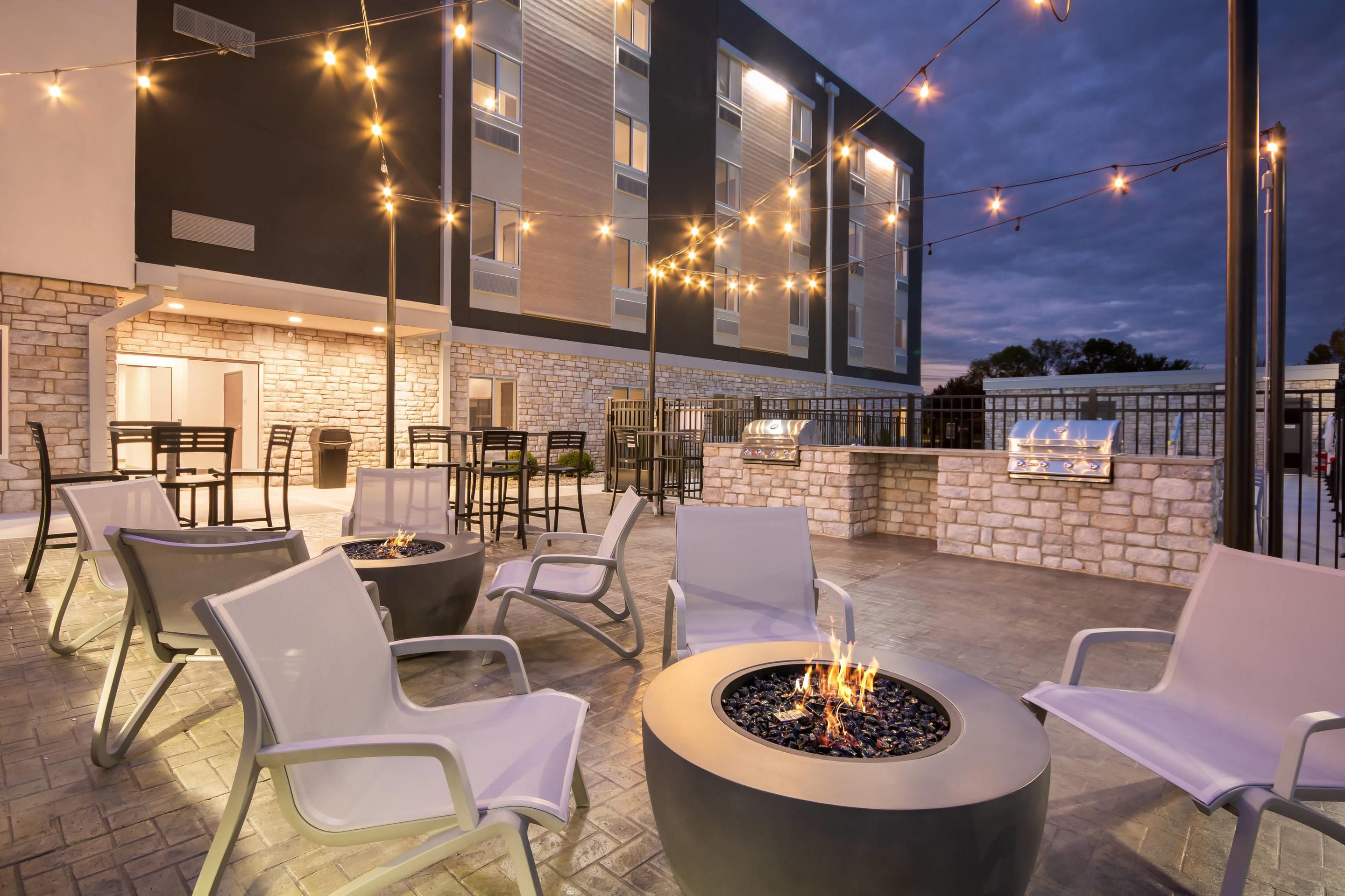 An outdoor patio with seating, a fire pit, and a barbecue grill.