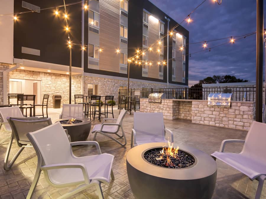 An outdoor patio with seating, a fire pit, and a barbecue grill.