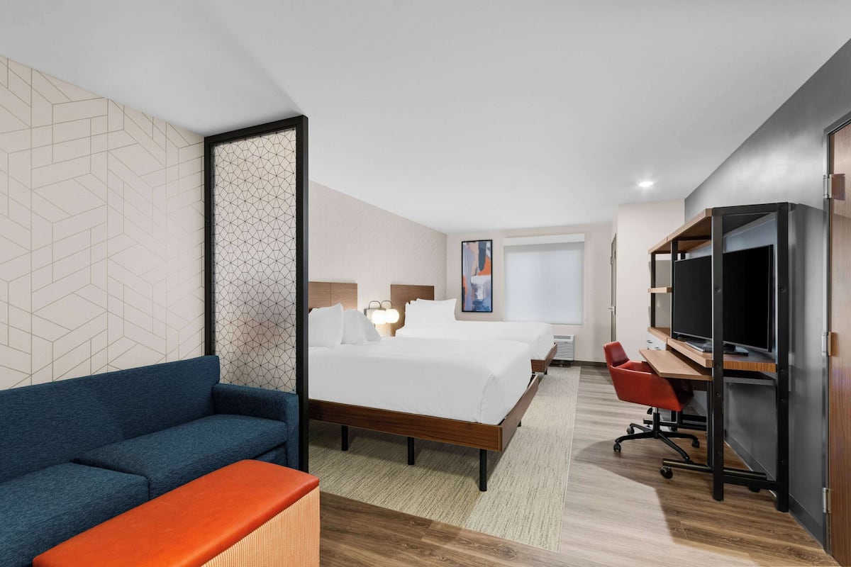 Una habitación de hotel con cama, escritorio, silla y televisión.