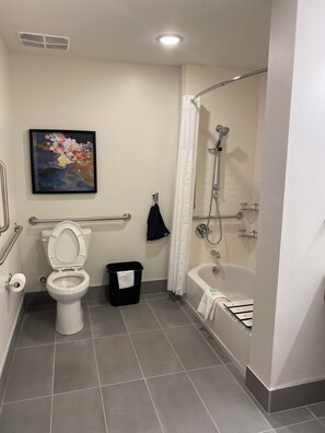 A bathroom with a toilet, a shower, a bathtub, and a handrail. - Everhome Suites Lexington - Horse Park (Lexington)