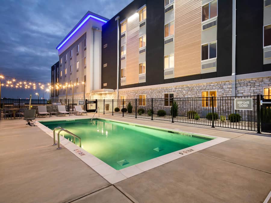 Un hotel con piscina, zona de estar al aire libre y fachada de piedra.