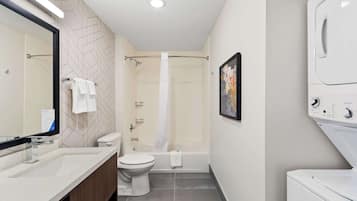 A modern bathroom with a shower, toilet, sink, and a built-in washing machine.