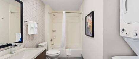 A modern bathroom with a shower, toilet, sink, and a built-in washing machine.