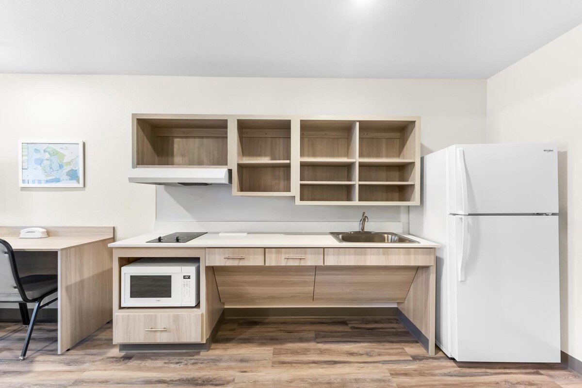 Una cocina moderna con microondas integrado, refrigerador y armarios de madera.