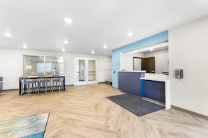 A modern reception area with a desk, chairs, and a waiting area with a table and chairs.