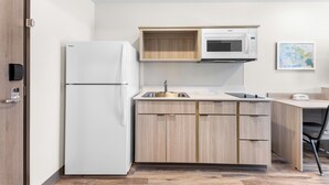 A compact kitchen with a built-in microwave, a sink, and a refrigerator. - Woodspring Suites Bluffdale Salt Lake City (Bluffdale)