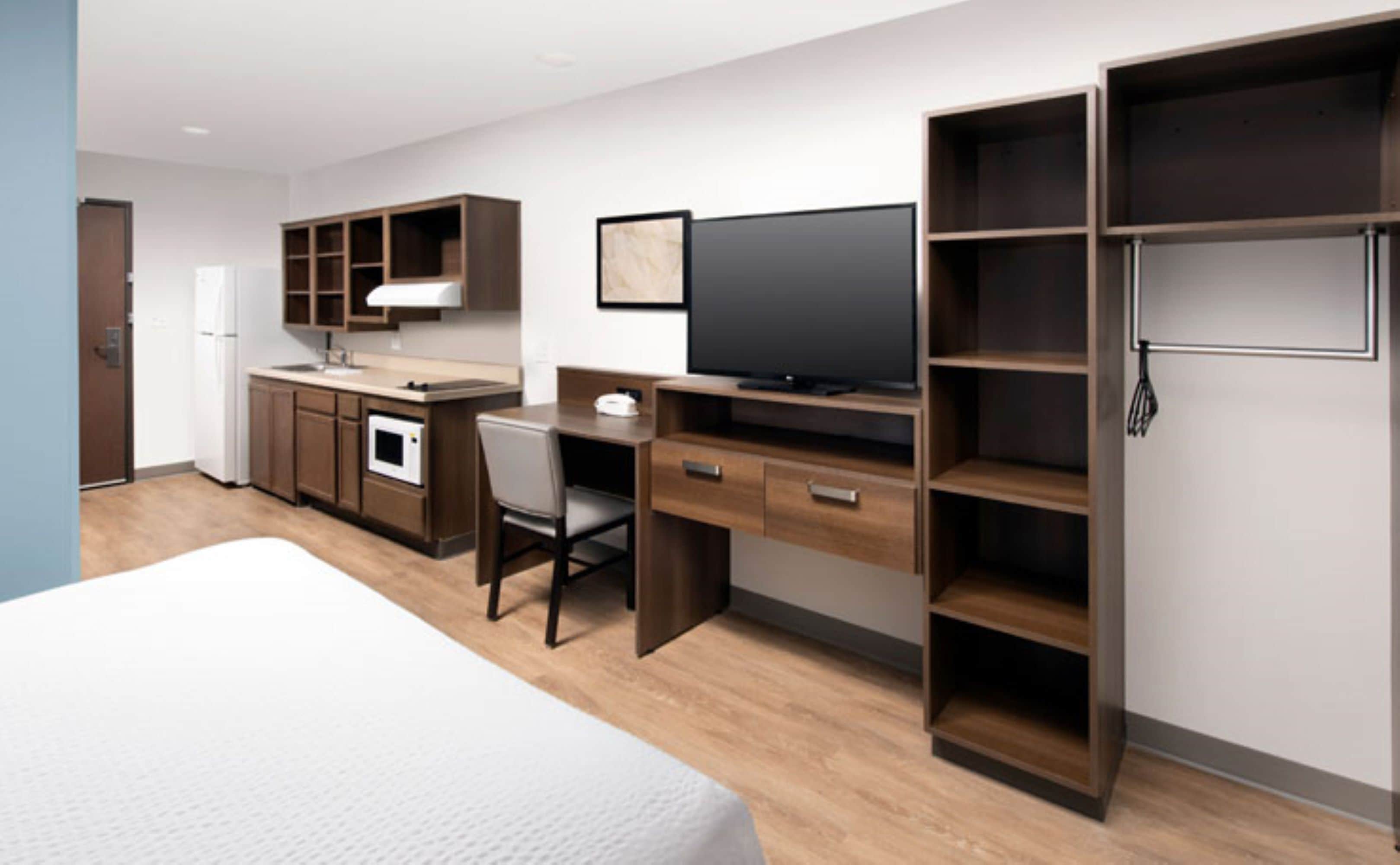 Una habitación de hotel con cama, escritorio, televisión, microondas y armario.